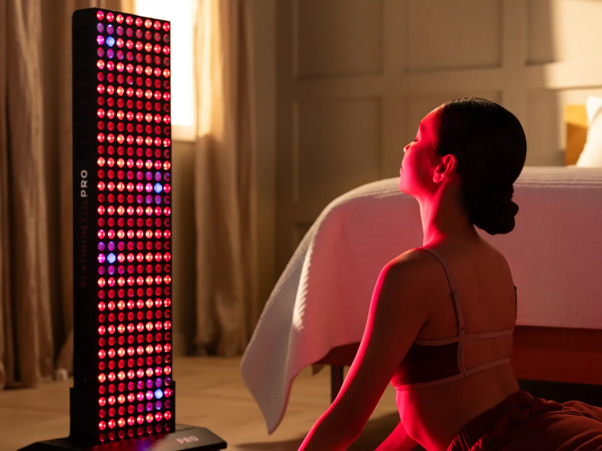 A woman sitting on a mat several feet from a floor standing BIOMAX PRO panel in a bedroom
