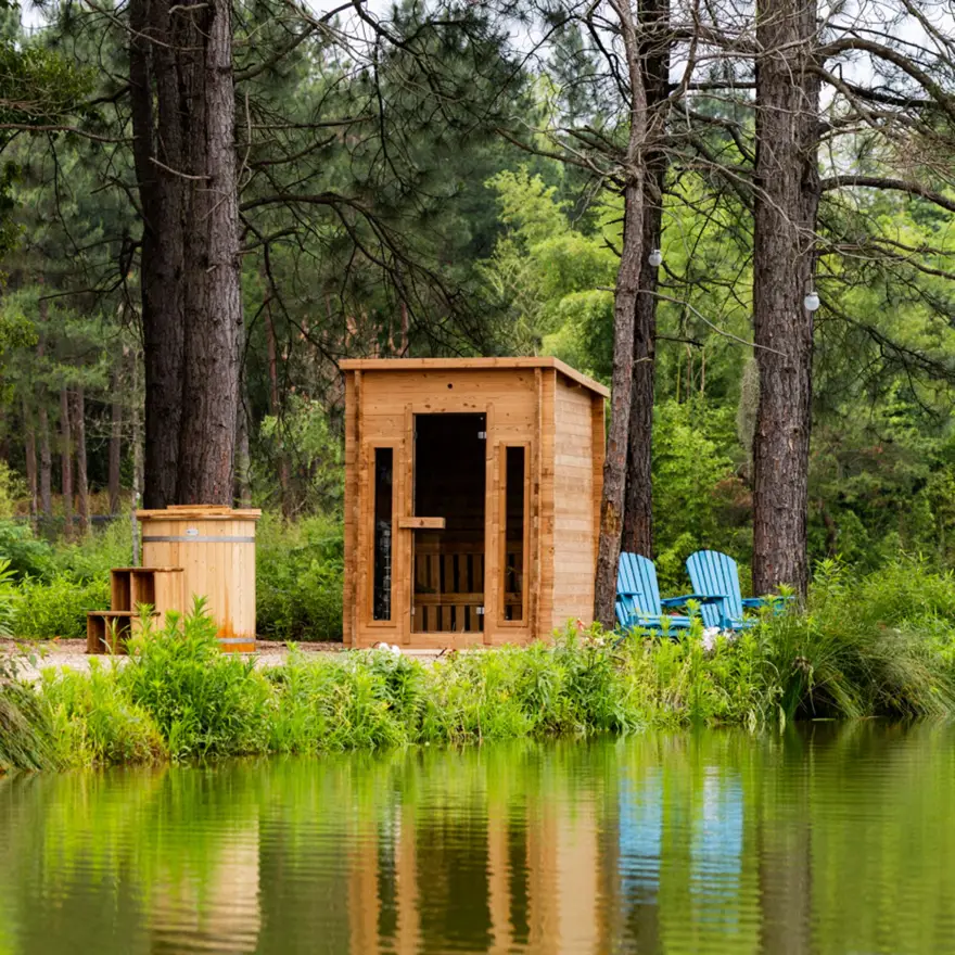 Cabin outdoor sauna installed beside a pond in a wooded setting