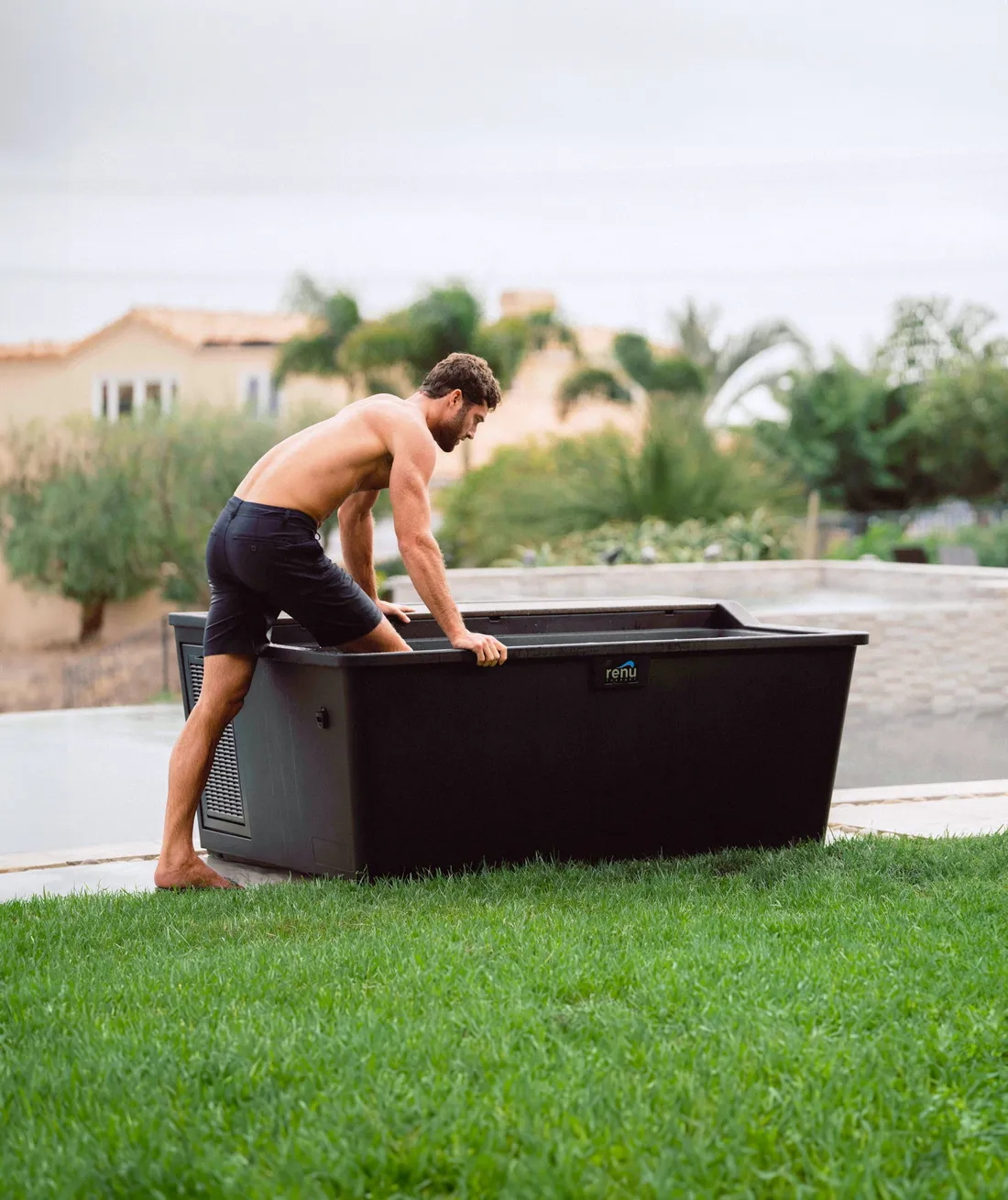Man leaning on the edge of a Renu Therapy Aurelius laydown cold plunge installed on a lawn