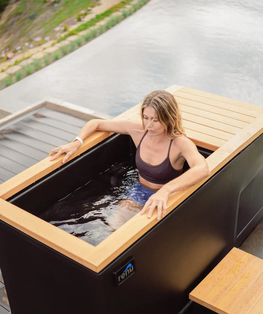 Close view of a woman in a Renu Therapy Cold Stoic cold plunge with the wooden breath deck at the rim