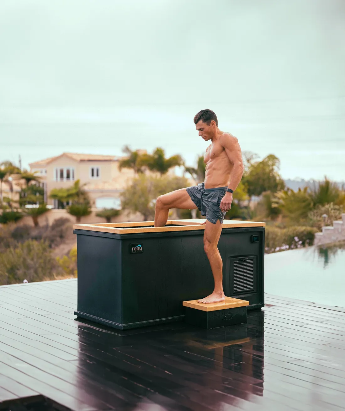 Man stepping up onto the breath deck of a Renu Therapy Cold Stoic 3.0 beside a swimming pool