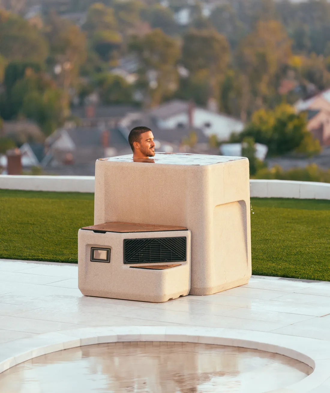 Man sitting on the step of a Renu Therapy Vero cold plunge outdoors