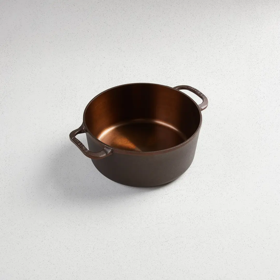 A Smithey cast iron Dutch oven with a polished bronze interior, seen from above.