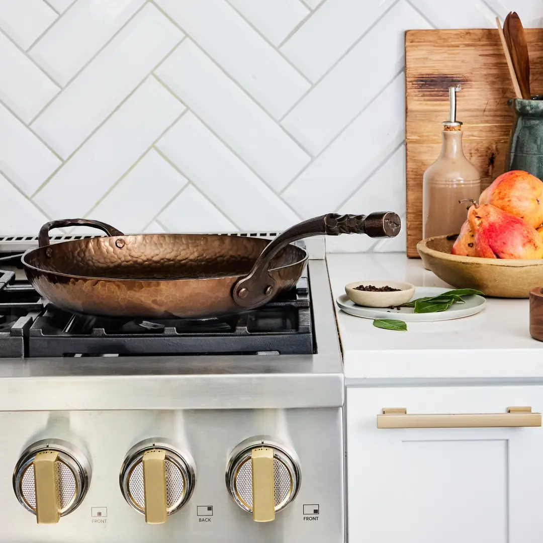 A Smithey carbon steel skillet resting on a home range in a bright kitchen.