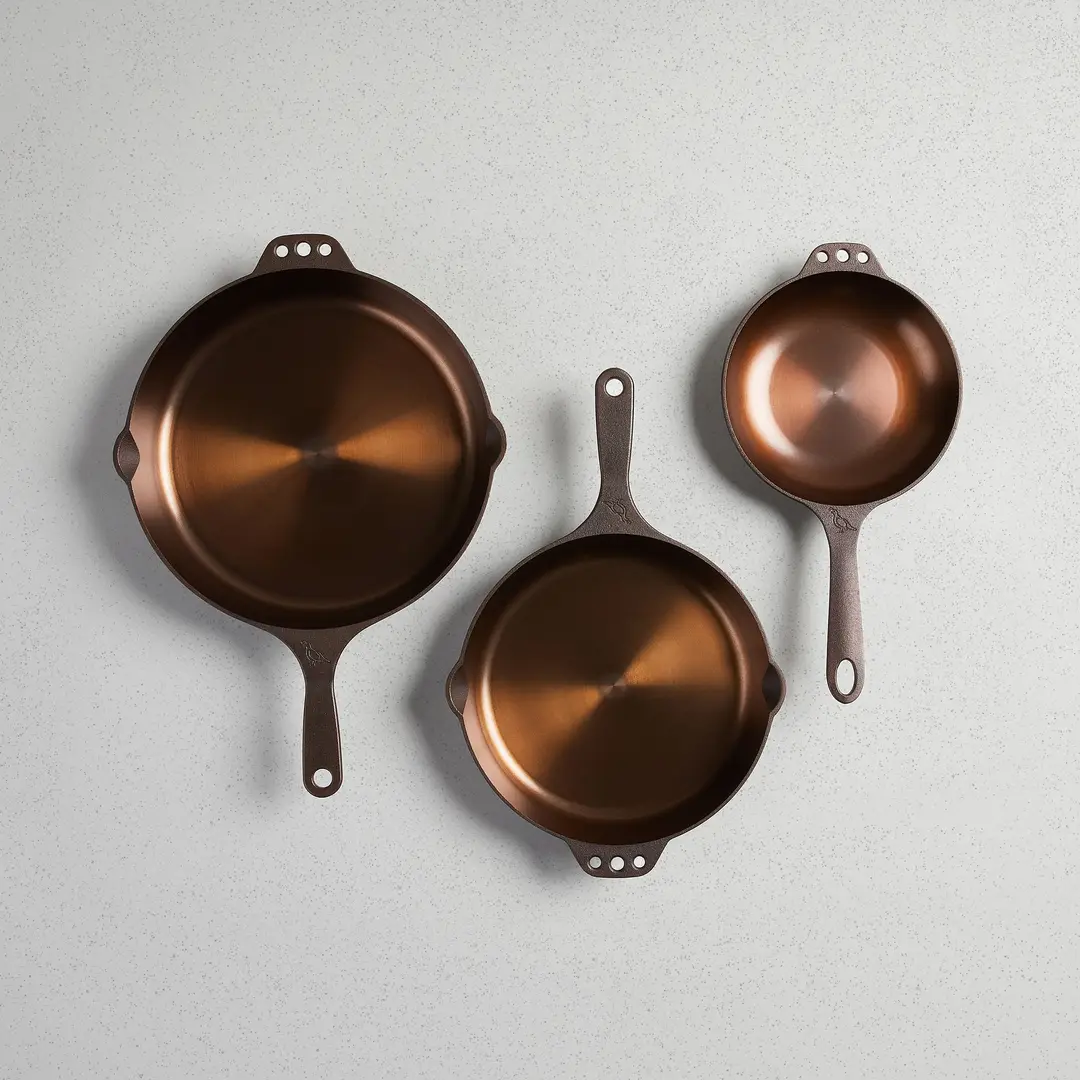 Three Smithey cast iron skillets in three sizes photographed from above on a pale background.
