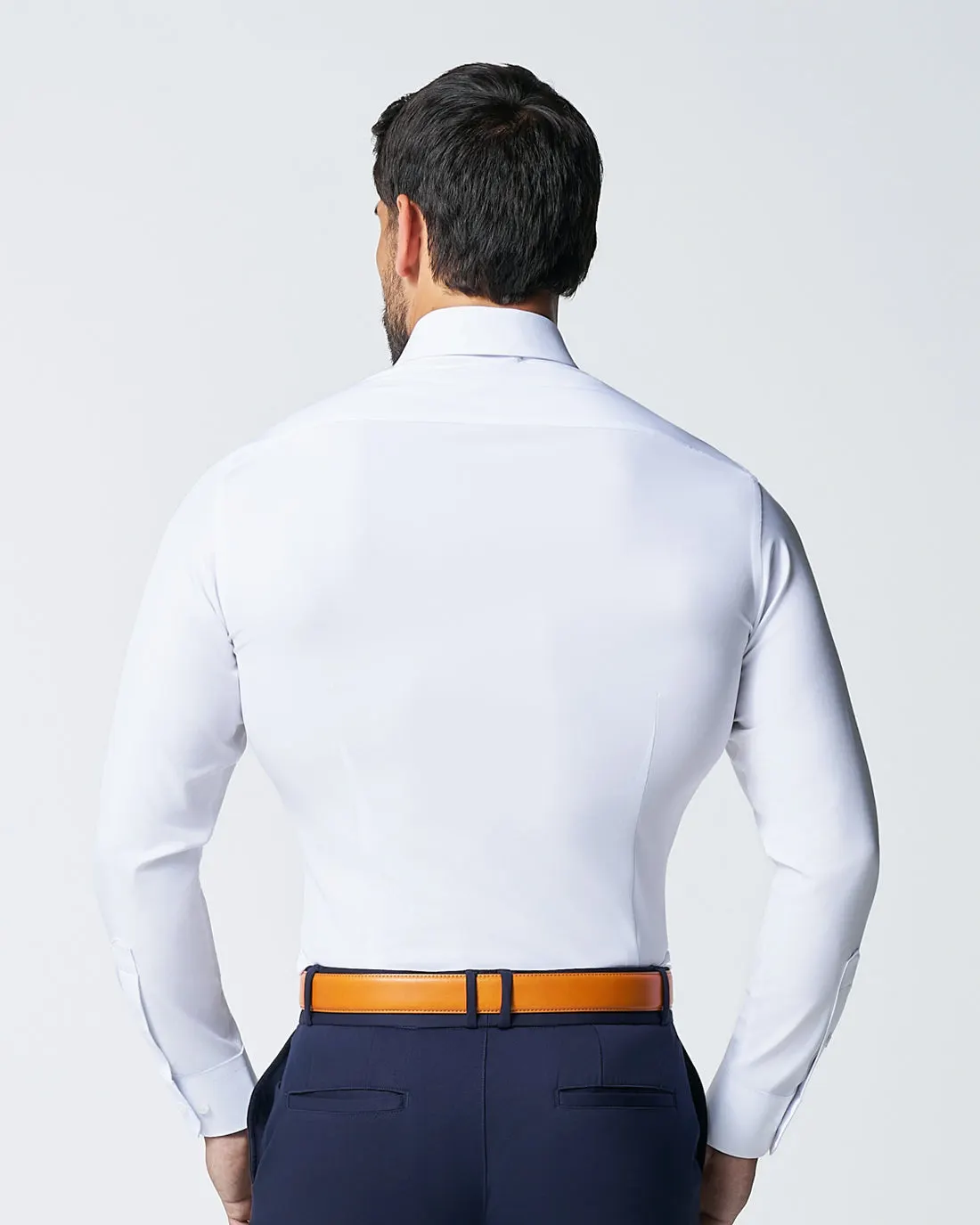 Back view of a white athletic fit dress shirt worn tucked in