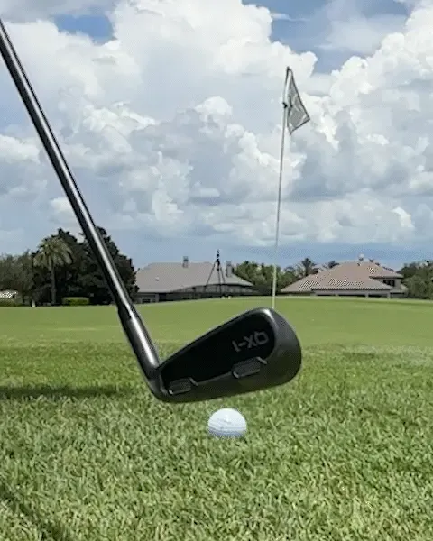 A golfer set up over a ball just off the fringe with the flag in the background
