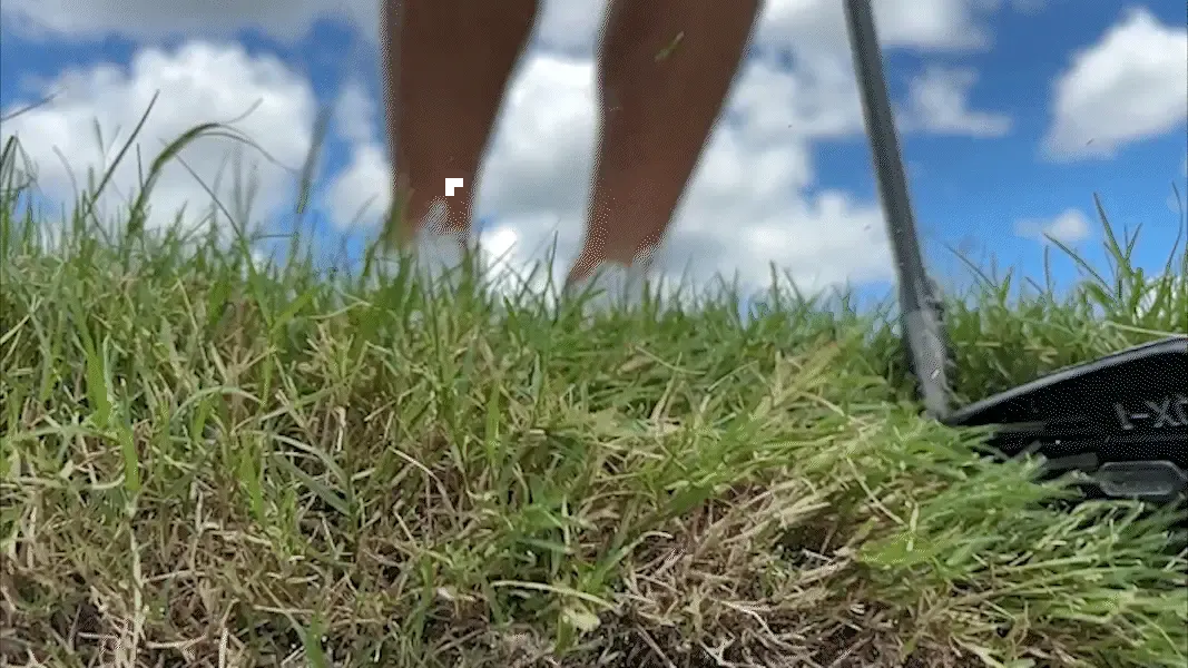 Low angle view of the wide QX-1 sole moving through thick rough behind the ball