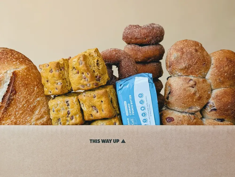 An opened Wildgrain box on a counter, filled with loaves, pastries and packaged items in an insulated liner