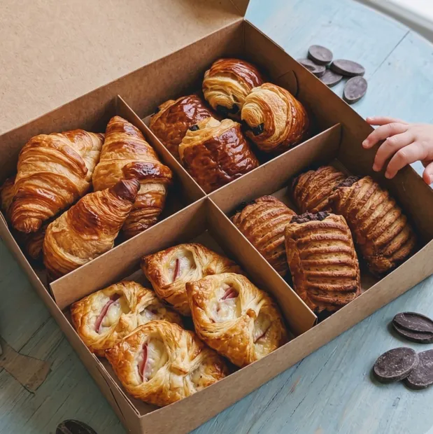 An open Wildgrain croissants box divided into four compartments holding different croissant varieties