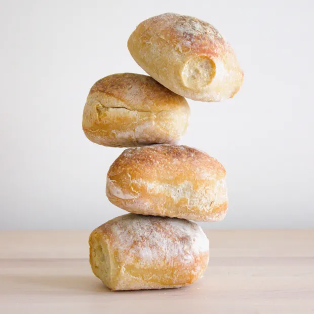 Four sourdough rolls stacked in a tower against a plain background