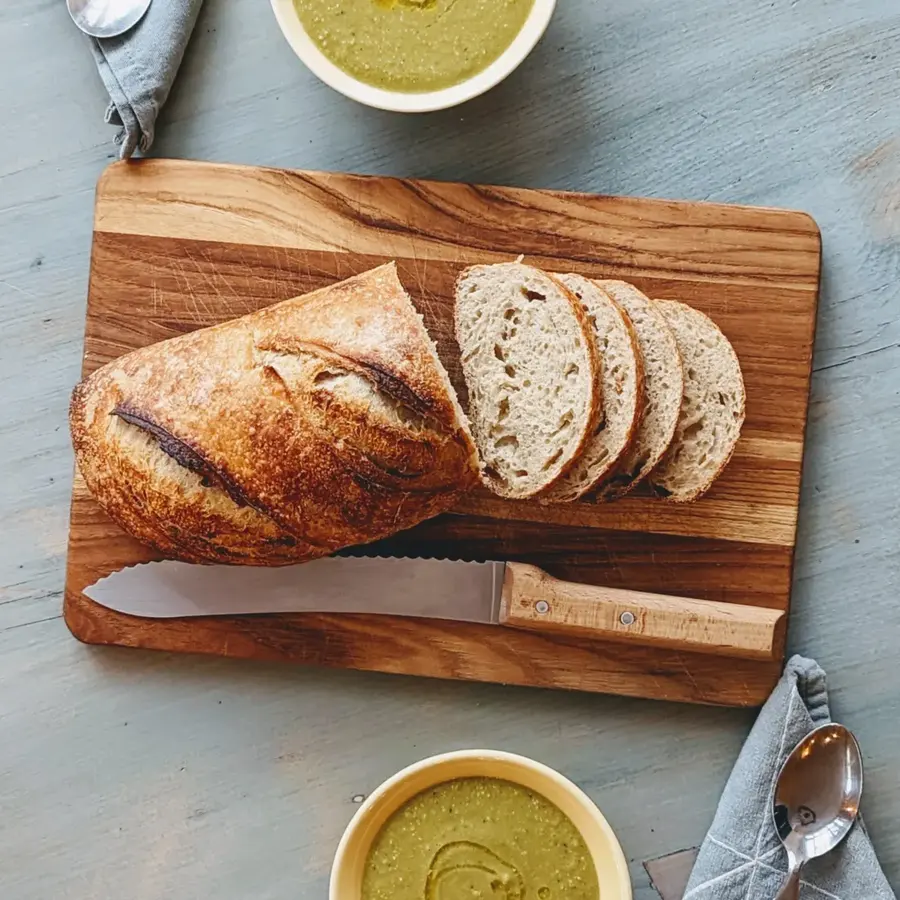 Thick slices of sourdough on a wooden board beside a small dish of olive oil