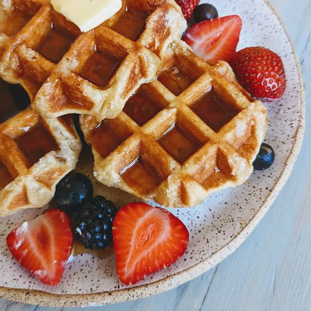 Belgian waffles on a plate with strawberries and blueberries