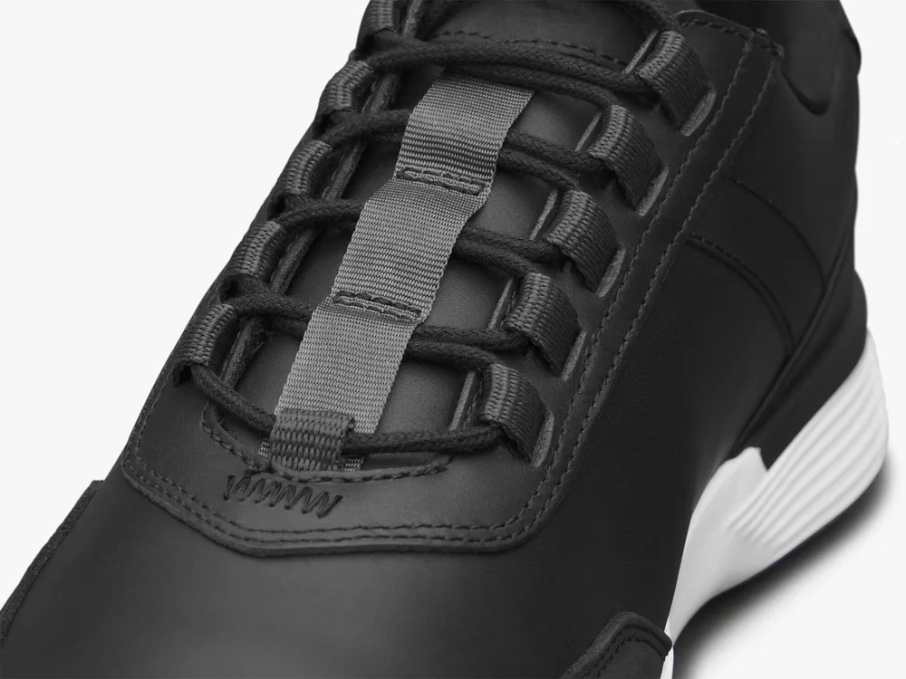 Close view of the full-grain leather upper and woven laces on the black Crossover Victory Trainer